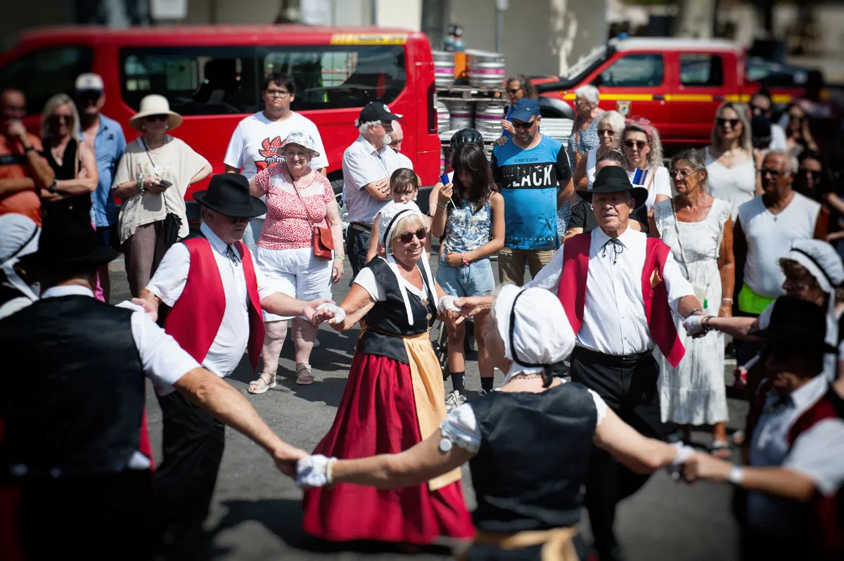 Les danseurs en cercle, mains dans les mains, devant la foule d’été